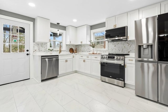 kitchen featuring light countertops, stainless steel appliances, decorative backsplash, and white cabinetry