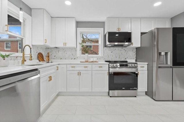 kitchen with a sink, appliances with stainless steel finishes, white cabinets, and light countertops