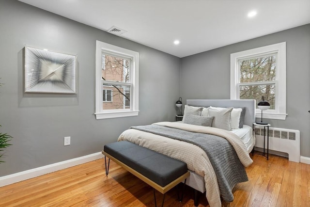bedroom featuring visible vents, baseboards, radiator heating unit, recessed lighting, and light wood finished floors