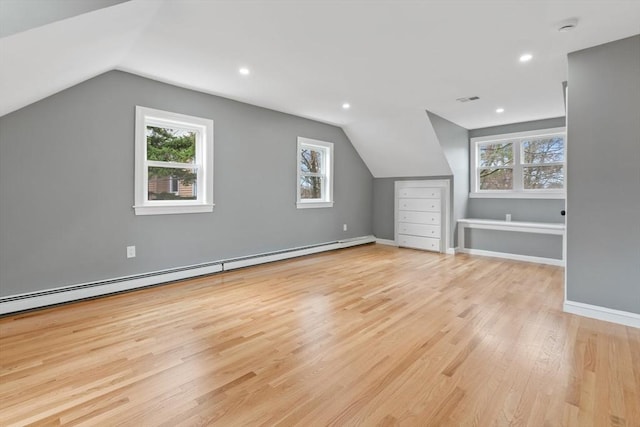 additional living space featuring plenty of natural light, wood finished floors, baseboard heating, and vaulted ceiling