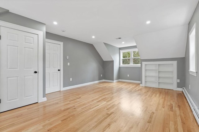 additional living space featuring light wood-style floors, baseboards, built in features, and baseboard heating