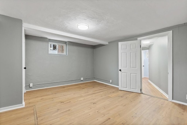 basement featuring baseboards, a textured ceiling, and wood finished floors