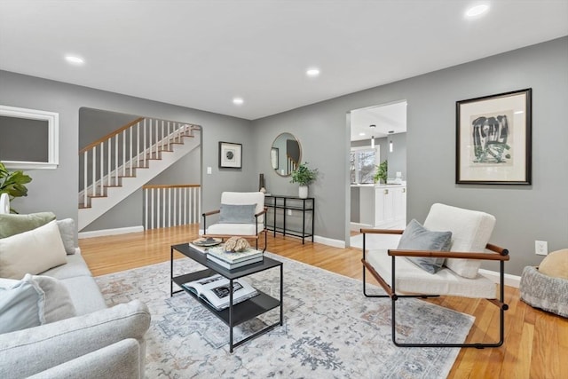 living room featuring recessed lighting, baseboards, wood finished floors, and stairway