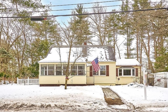 view of front of house with a sunroom, a chimney, and fence