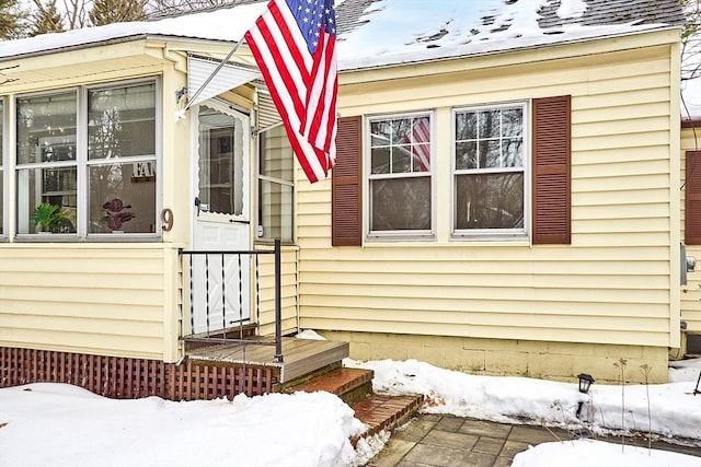 snow covered property with roof with shingles