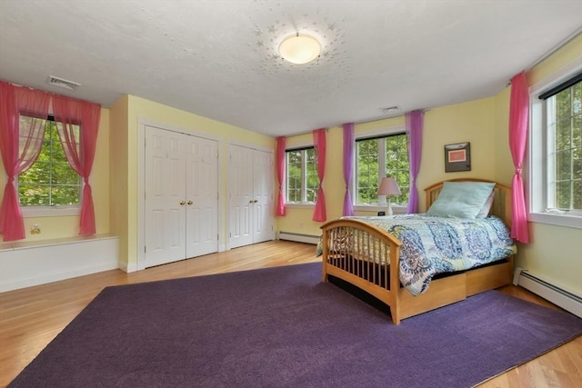1 Fox Hunt Ln, Winchester, MA 01890 - bedroom with a baseboard heating unit, wood finished floors, and two closets