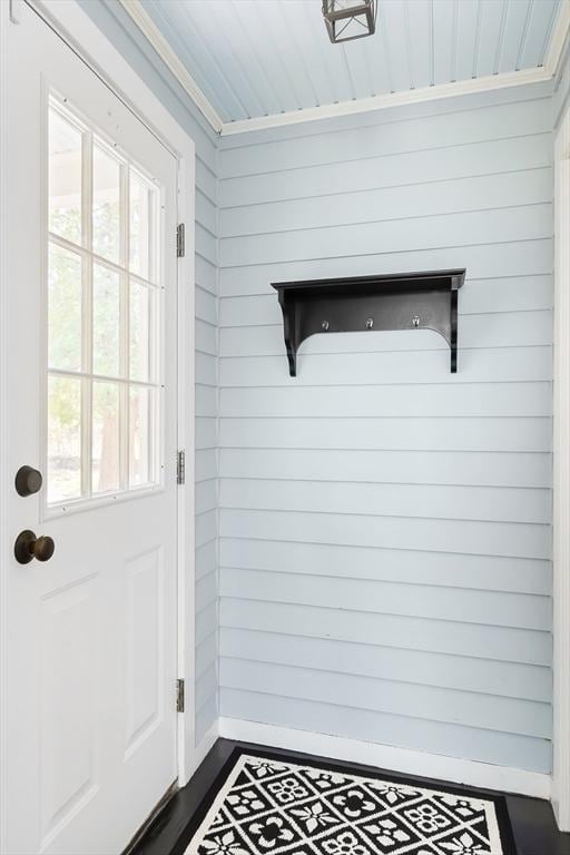 doorway to outside with wood walls