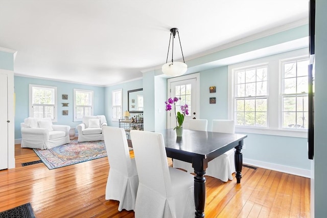 dining room featuring crown molding, baseboards, and light wood-style flooring