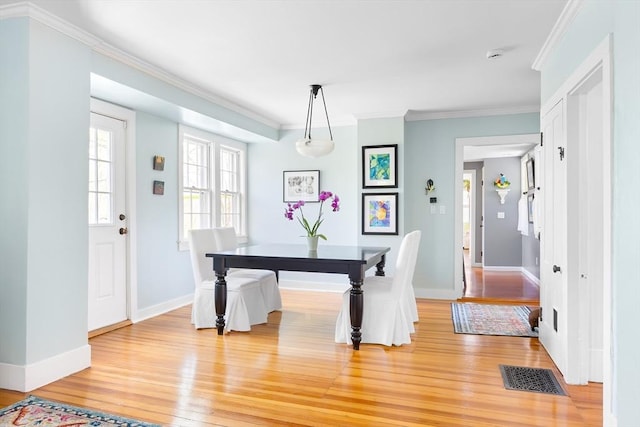 dining room featuring light wood-style floors, baseboards, crown molding, and visible vents