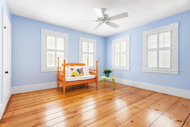living area featuring light wood-style floors, baseboards, and a ceiling fan