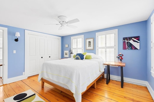 bedroom with a ceiling fan, baseboards, light wood-style flooring, and a closet