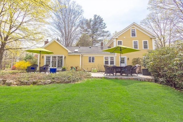 rear view of property featuring a lawn, a patio, and a chimney
