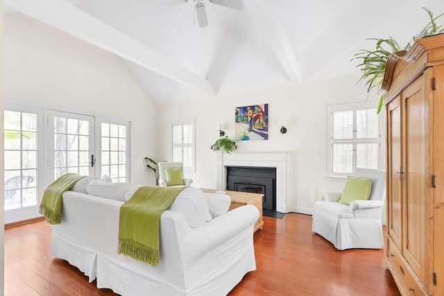 living room with a fireplace with flush hearth, beamed ceiling, and wood finished floors