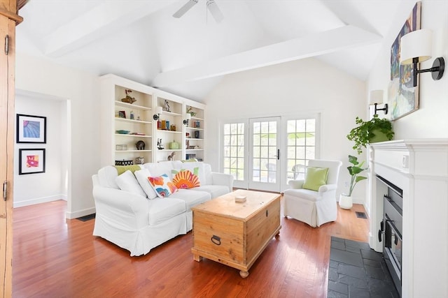 living room with dark wood-style flooring, ceiling fan, lofted ceiling with beams, baseboards, and a fireplace with flush hearth