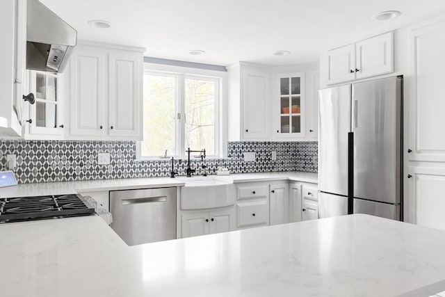 kitchen featuring backsplash, a sink, white cabinets, glass insert cabinets, and stainless steel appliances