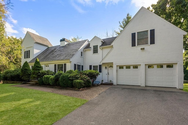 view of front of home featuring driveway, a chimney, roof with shingles, a front yard, and a garage