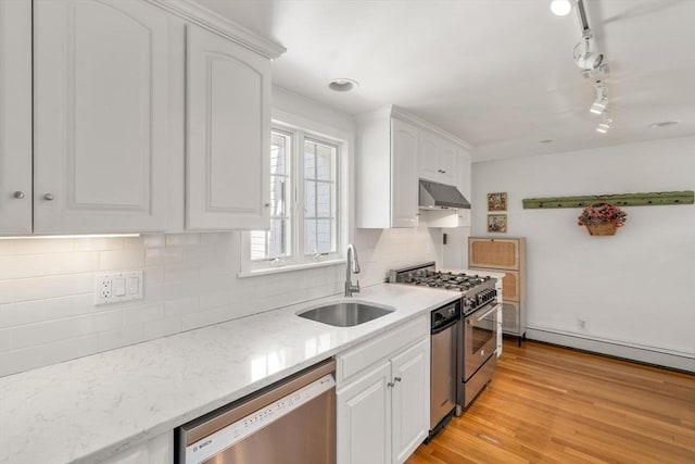 kitchen with backsplash, appliances with stainless steel finishes, a sink, under cabinet range hood, and white cabinetry