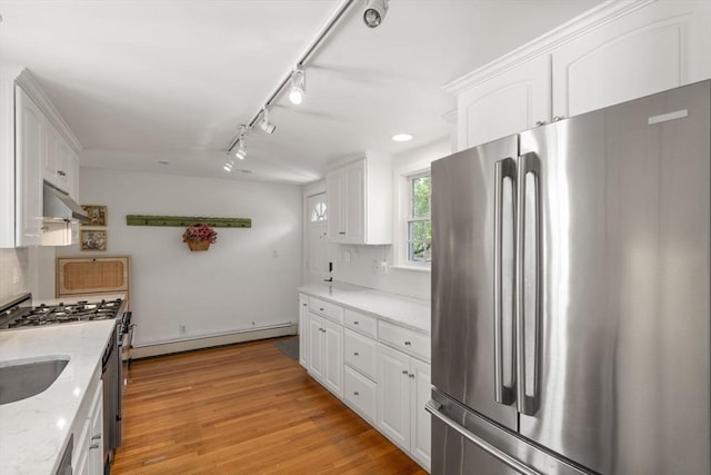 kitchen featuring under cabinet range hood, appliances with stainless steel finishes, a baseboard heating unit, and white cabinets