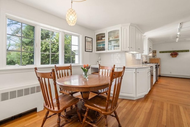 dining area featuring radiator, rail lighting, and light wood-style flooring
