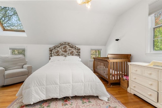 bedroom with multiple windows, light wood-type flooring, and lofted ceiling with skylight