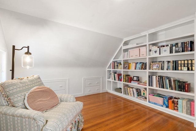 living area featuring baseboards, vaulted ceiling, built in features, and wood finished floors