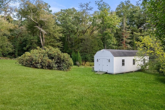 view of yard featuring an outbuilding, a storage shed, and a forest view