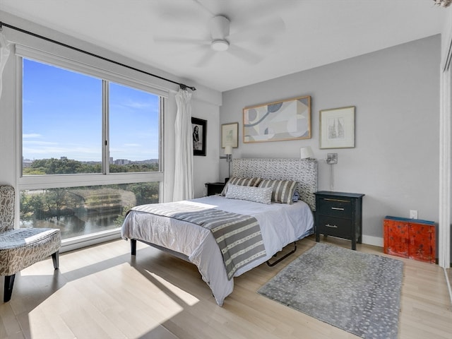 bedroom with light hardwood / wood-style floors, ceiling fan, and baseboard heating