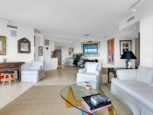 living room with rail lighting and light hardwood / wood-style flooring