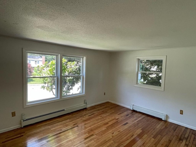 spare room featuring baseboards, wood-type flooring, a textured ceiling, a baseboard heating unit, and baseboard heating