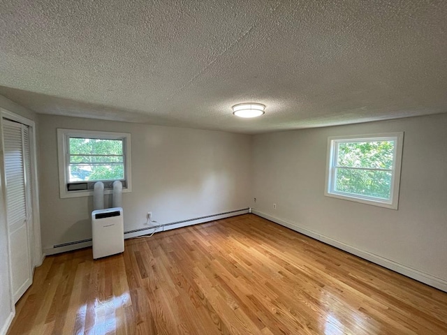 unfurnished bedroom with a closet, light wood-type flooring, baseboard heating, and a textured ceiling