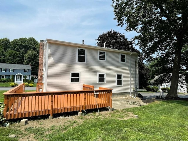 back of property featuring a yard, a patio, a wooden deck, and a chimney