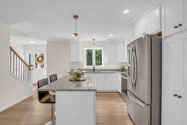 kitchen featuring pendant lighting, a breakfast bar, light hardwood / wood-style floors, and appliances with stainless steel finishes