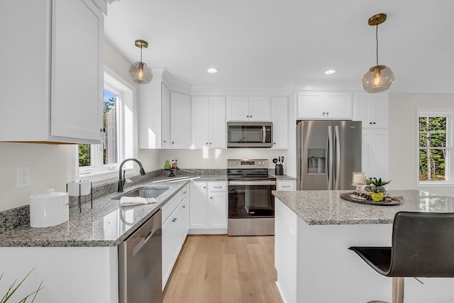 kitchen featuring a wealth of natural light, stainless steel appliances, sink, pendant lighting, and white cabinetry