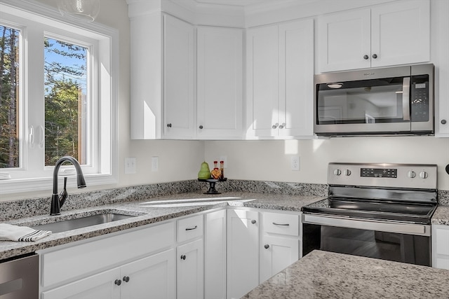 kitchen with white cabinets, stainless steel appliances, light stone countertops, and sink