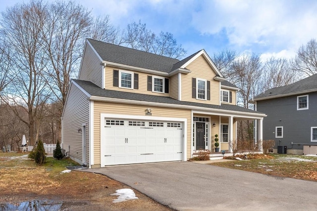 front facade with a garage, a porch, and central AC unit