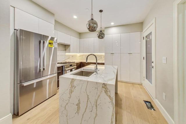 kitchen with stainless steel appliances, a sink, modern cabinets, white cabinets, and recessed lighting