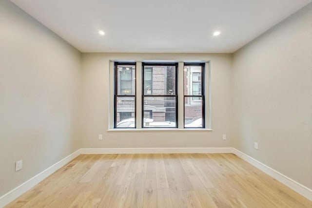 unfurnished room featuring light wood finished floors, baseboards, and recessed lighting