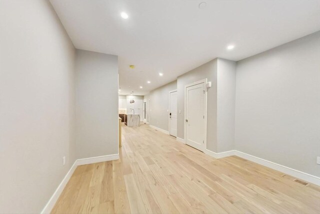 hallway featuring light wood-style floors, baseboards, and recessed lighting