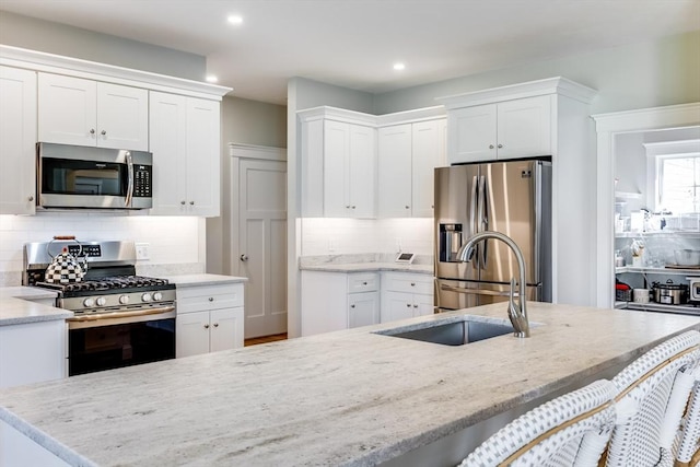 kitchen featuring stainless steel appliances, tasteful backsplash, white cabinetry, light stone countertops, and recessed lighting