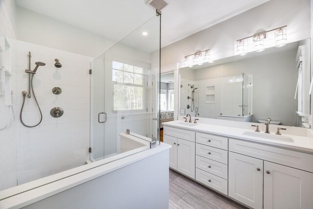 bathroom featuring a shower stall, double vanity, and recessed lighting