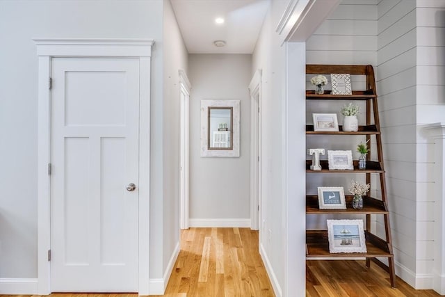corridor featuring light wood-type flooring and baseboards