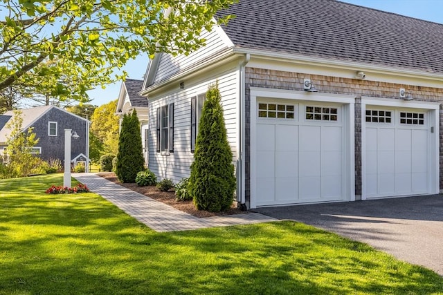 view of side of home featuring asphalt driveway, a lawn, and a shingled roof