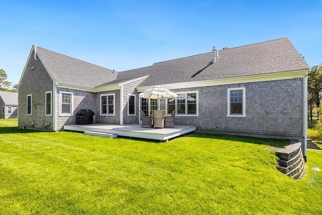 back of property with a yard, a wooden deck, and a shingled roof