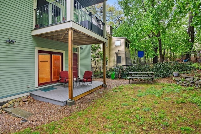 rear view of house featuring a balcony, fence, and a wooden deck