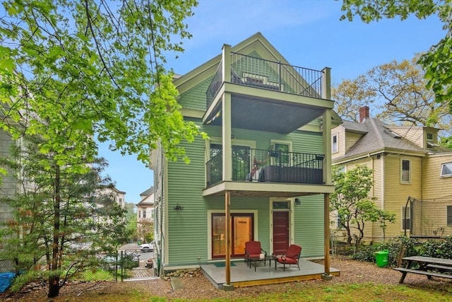 rear view of property featuring a balcony, a patio area, and fence
