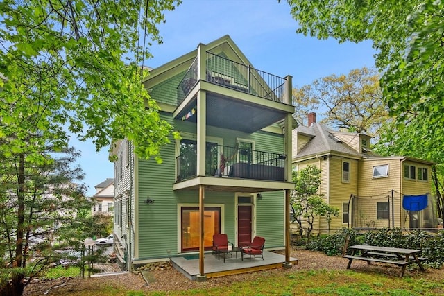 back of property with a balcony, a patio, fence, and a gate
