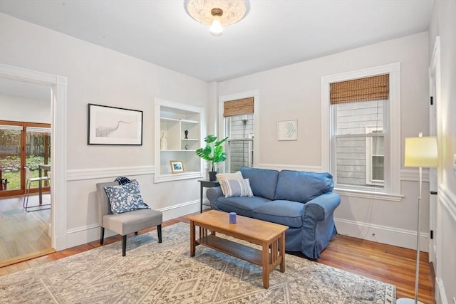 living room with wood finished floors, baseboards, and built in shelves