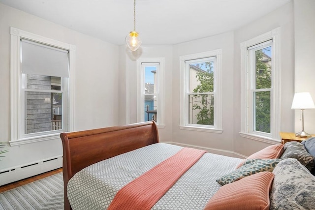 bedroom with a baseboard radiator and wood finished floors