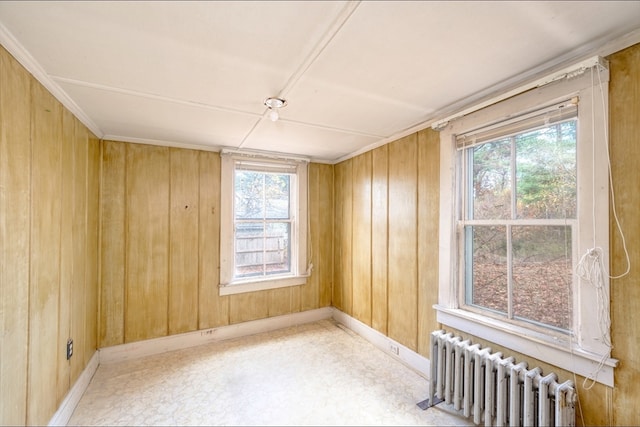 unfurnished room featuring radiator heating unit and wood walls