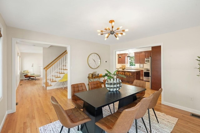 dining area with stairs, baseboards, visible vents, a notable chandelier, and light wood-style floors